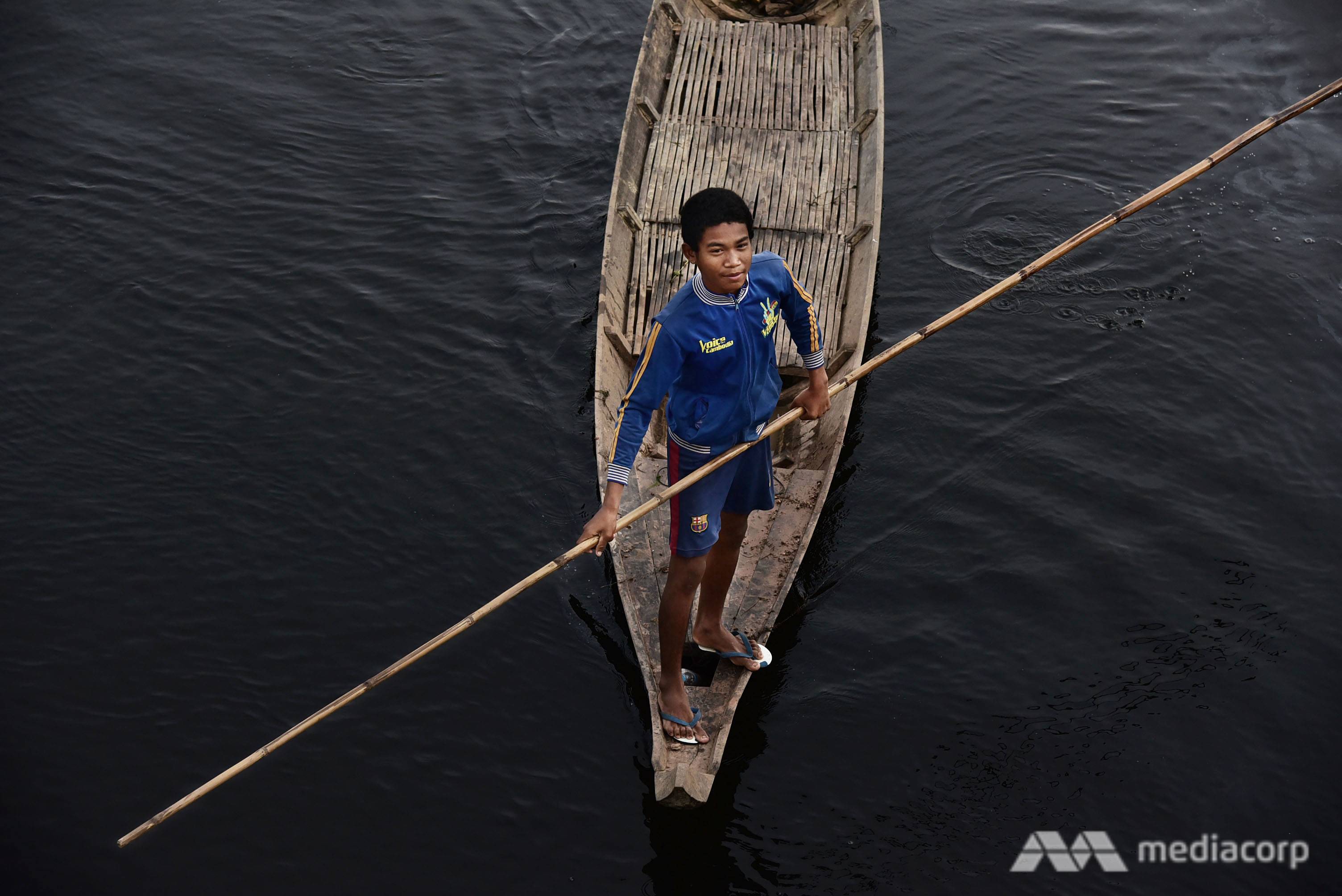 A boy rows his boat on submerged land, heading towards a floating rice field. Many farmers in Kampong Thom province still grow rice in deep water during flooding season, when water from Tonle Sap River inundates a vast area of land. (Photo: Pichayada Promchertchoo)