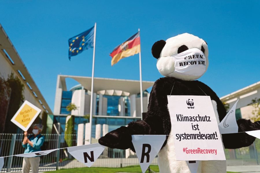 An activist dressed as a panda bear, wearing a poster reading ‘Climate protection is system relevant’, during a protest against the German government’s rescue plans for the car industry, in front of the Chancellery in Berlin on Tuesday. -AFP pic