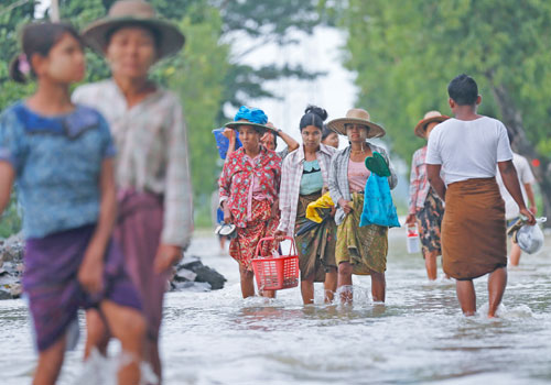 People walk through floodwater in Kyaunggon township of Ayeyarwady Region in August 2015. Photo: EPA