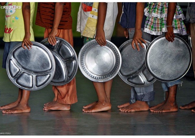 Children holding plates wait in queue to receive food at an orphanage run by an NGO in Chennai, India - REUTERS