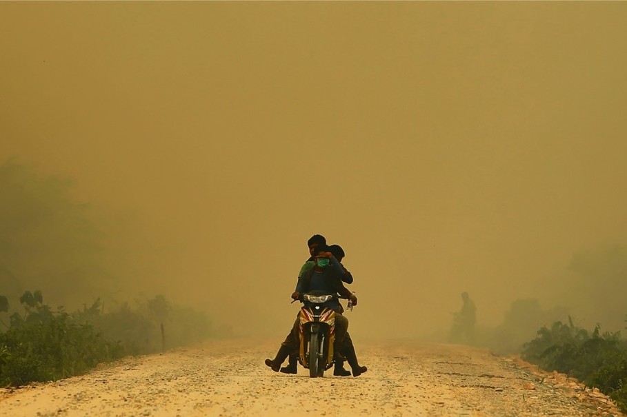 Three children persevere through haze in Dumai, Sumatra, after a series of forest fires and hotspots sent air quality to dangerous levels in June. (Reuters Photo)