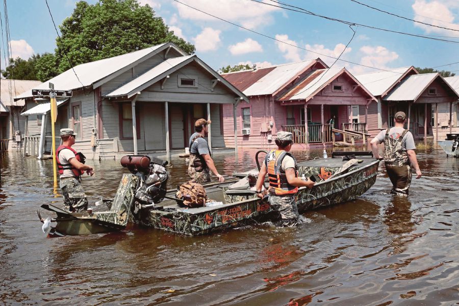 Members of the Texas National Guard wading through floodwaters in Orange, Texas, on Saturday. People’s emissions of heat-trapping gases have increased the likelihood and severity of heat waves, extreme rainfall and storm surges. (AFP PIC)