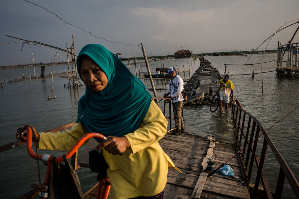 Villagers cross the bridge at the land which has been sinking below sea level at Bedono village, Indonesia. 