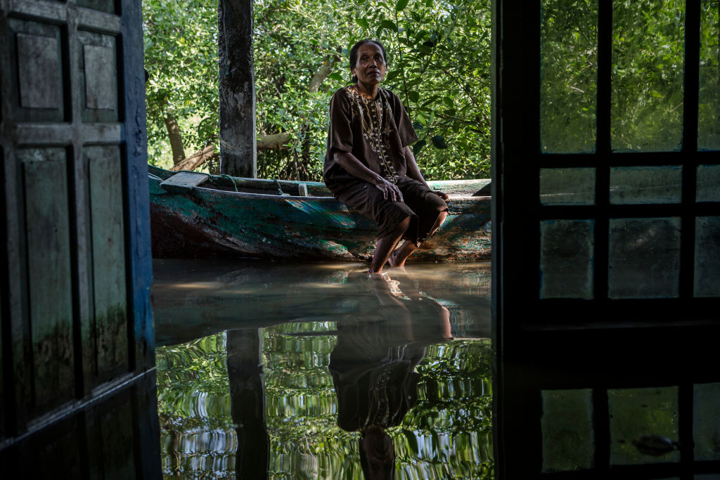 Pasijah (45), sits inside her house submerged by rising sea levels at Bedono village, Indonesia. Pasijah, with her family has been twelve years living in her flooded home, she can not leave her house because she has no money to move to another place.