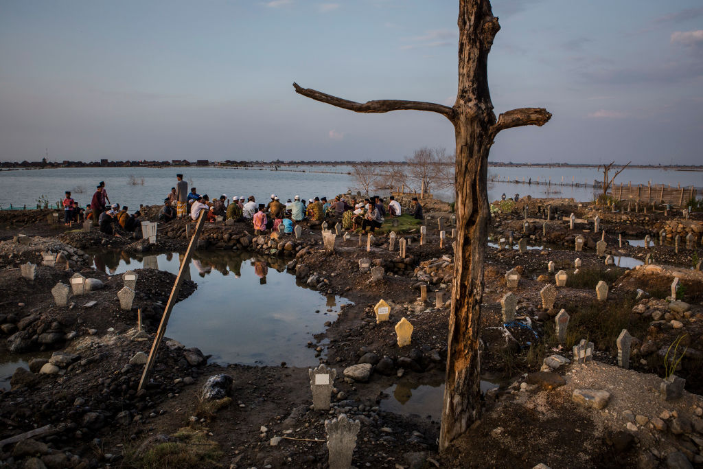 Villagers pray at the cemetery that is surrounded by rising sea levels at Bedono village