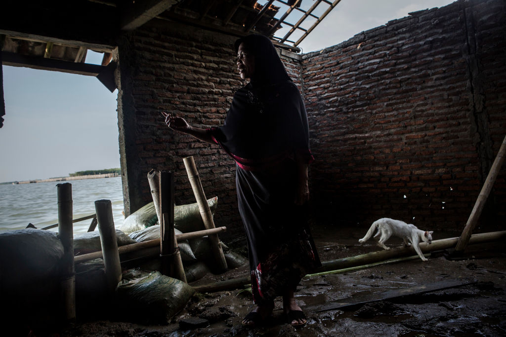 Karimah (52), showing her destroyed house from rising sea levels at Bedono village, Indonesia. Karimah, has been twenty-seven years living in her flooded home, she can not leave her house because she has no money to move to another place.