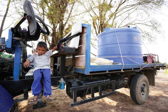 A boy sits on a water delivery vehicle in Banteay Meanchey province. Hong Menea