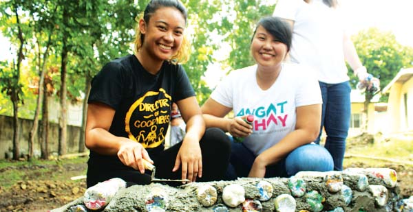 ECO-BUILDERS — The Circle Hostel’s PR/Events Coordinator Jermaine Choa-Peck (left) and a volunteer from Angat Buhay build a planter box made of eco-bricks for an elementary school in Taysan, Batangas. Eco-bricks are plastic bottles stuffed with non-biodegradable wastes.