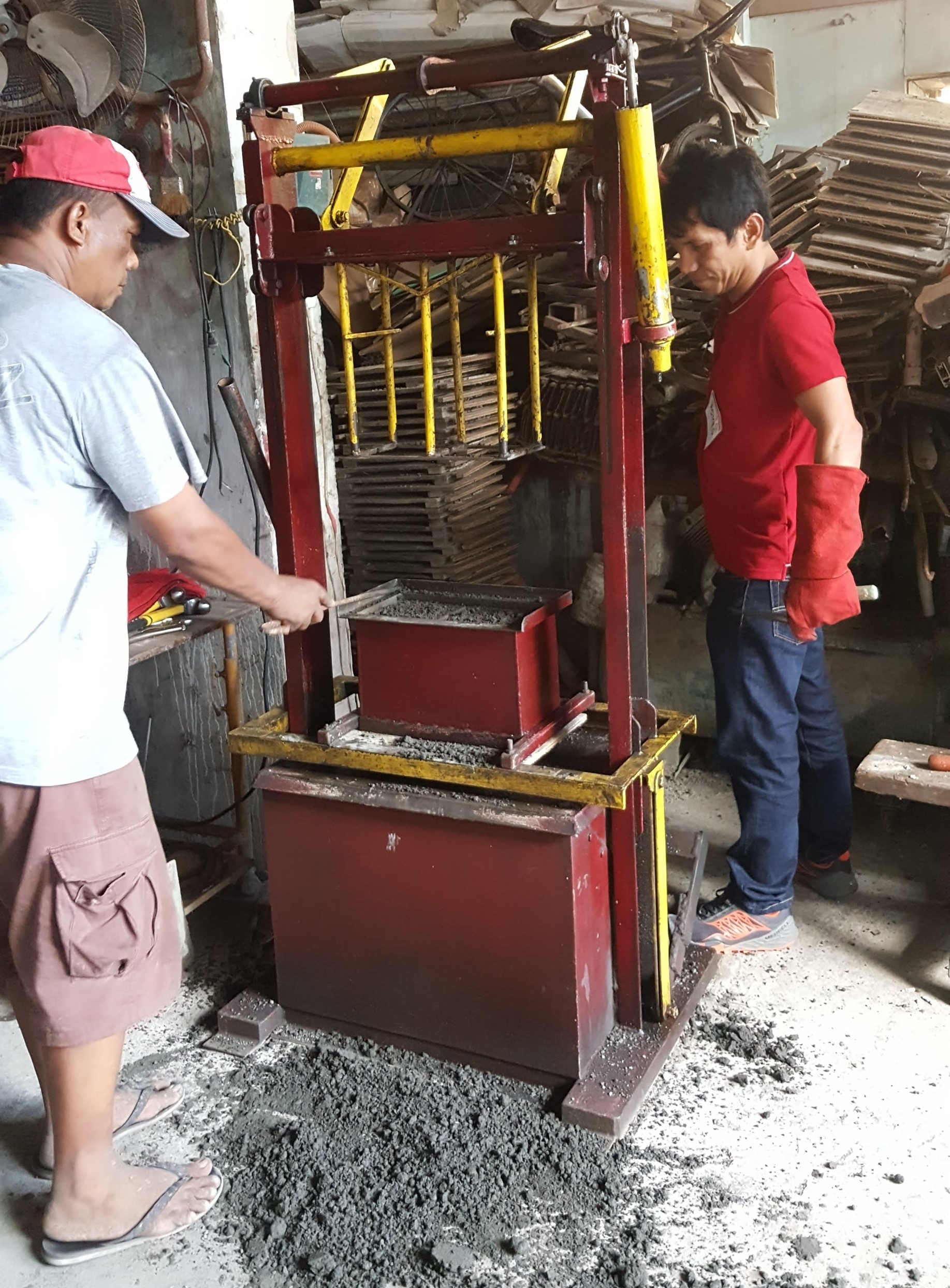 One of the workshop participants tests the ease of use of the multi-blocks vibrating machine developed by BISCAST to create their own hollow blocks.