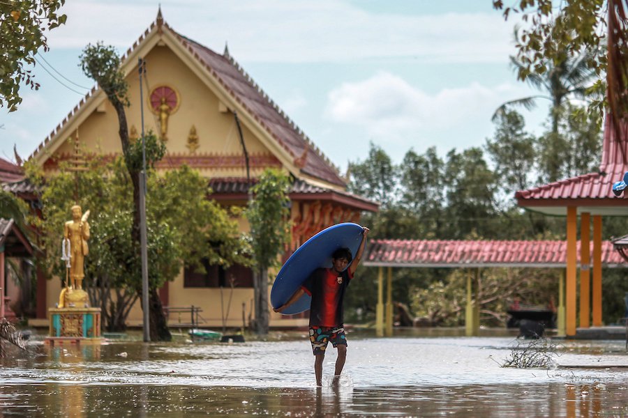 A man carries a board as he walks through a flooded road near a temple after tropical storm Pabuk hit the southern province of Nakhon Si Thammarat. (Reuters pic)