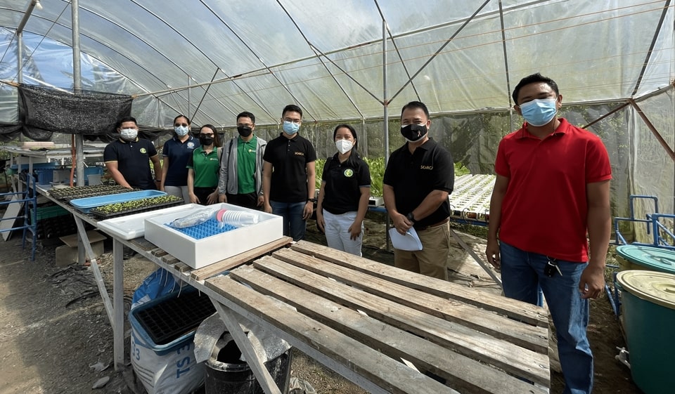 SEARCA and GLI pose for a photo opportunity inside the NIU Greens Hydroponics farm before the start of the distribution of hydroponics kits. The SEARCA delegation comprised Dr. Romeo V. Labios (second from right), Technical Advisor for Partnerships; Ms. Ma. Victoria D. Bravo (second from left), Executive Assistant for Programs; Mr. Pasiona (fourth from left); Mr. Felix (fifth from left); and Ms. Marie Cris P. Mendoza (third from left), Property and Supply Assistant. Also, in the photo is the GLI team led by Vice President Mr. Aniciete (leftmost).
