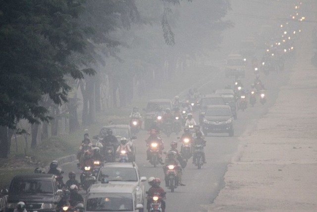 TOXIC AIR. Commuters travel along a road as thick haze blankets Pekanbaru on September 16, 2014.Forza Alfachrozie/AFP
