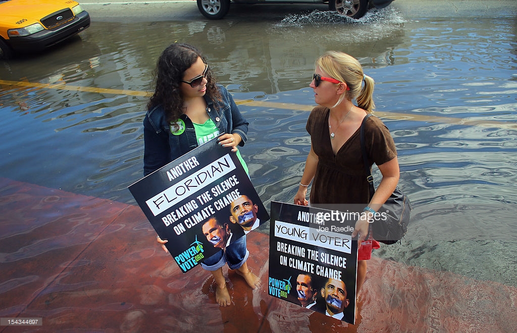 Jacquie Ayala (L) and Amanda Lawrence stand in a flooded street as they and others call on the presidential candidates to talk about their plans to fight climate change on October 18, 2012 in Miami Beach, Florida. Some of the streets on Miami Beach are flooded due to unusually high tides that the protesters felt are due to rising seas, which are connected to global warming and climate change. Published reports indicate that Florida ranks as the most vulnerable state to sea-level rise, with some 2.4 million people, 1.3 million homes and 107 cities at risk from a four-foot rise in sea levels.
