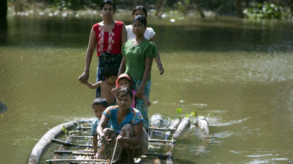 Flood victims ride a bamboo raft over a flooded road to receive relief items from private donors in Thabaung township, Ayeyarwaddy delta, Myanmar, Aug. 29, 2015.