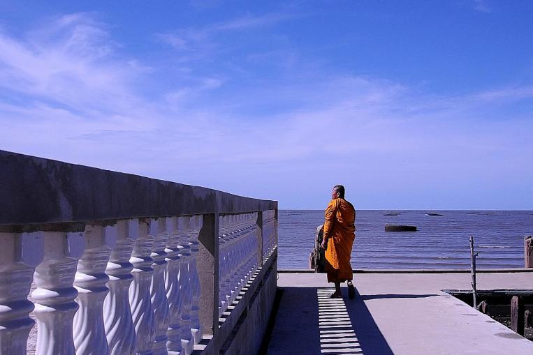 Phra Somnuek Athipanyo, the abbot of Wat Khun Samut, a Buddhist temple on the coast of the Gulf of Thailand some 30km south of Bangkok, patrols the parapet inspecting his temple's defenses against the sea. ST PHOTO: NIRMAL GHOSH