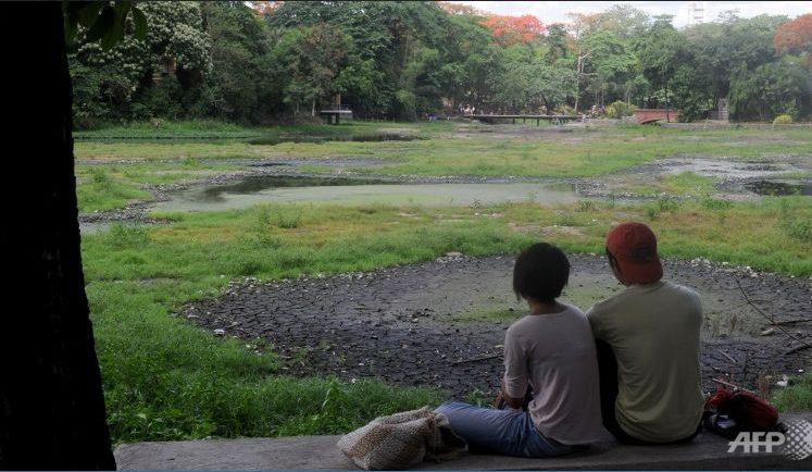 A Filipino couple watches the cracked bottom of a dried lake in a park in a suburb of Manila on June 6, 2015. (Photo: AFP/Jay Directo)