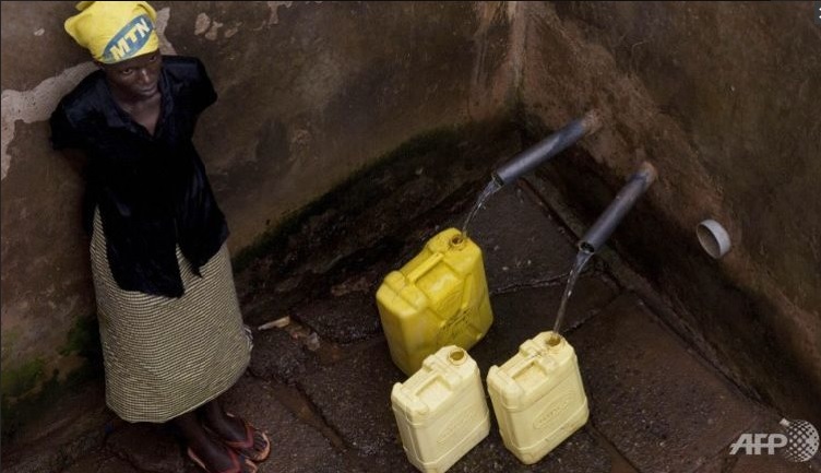 A woman fills jugs with water at a water distribution point in the Naguru Go Down Slum in Kampala.(Photo: AFP/Walter Astrada)
